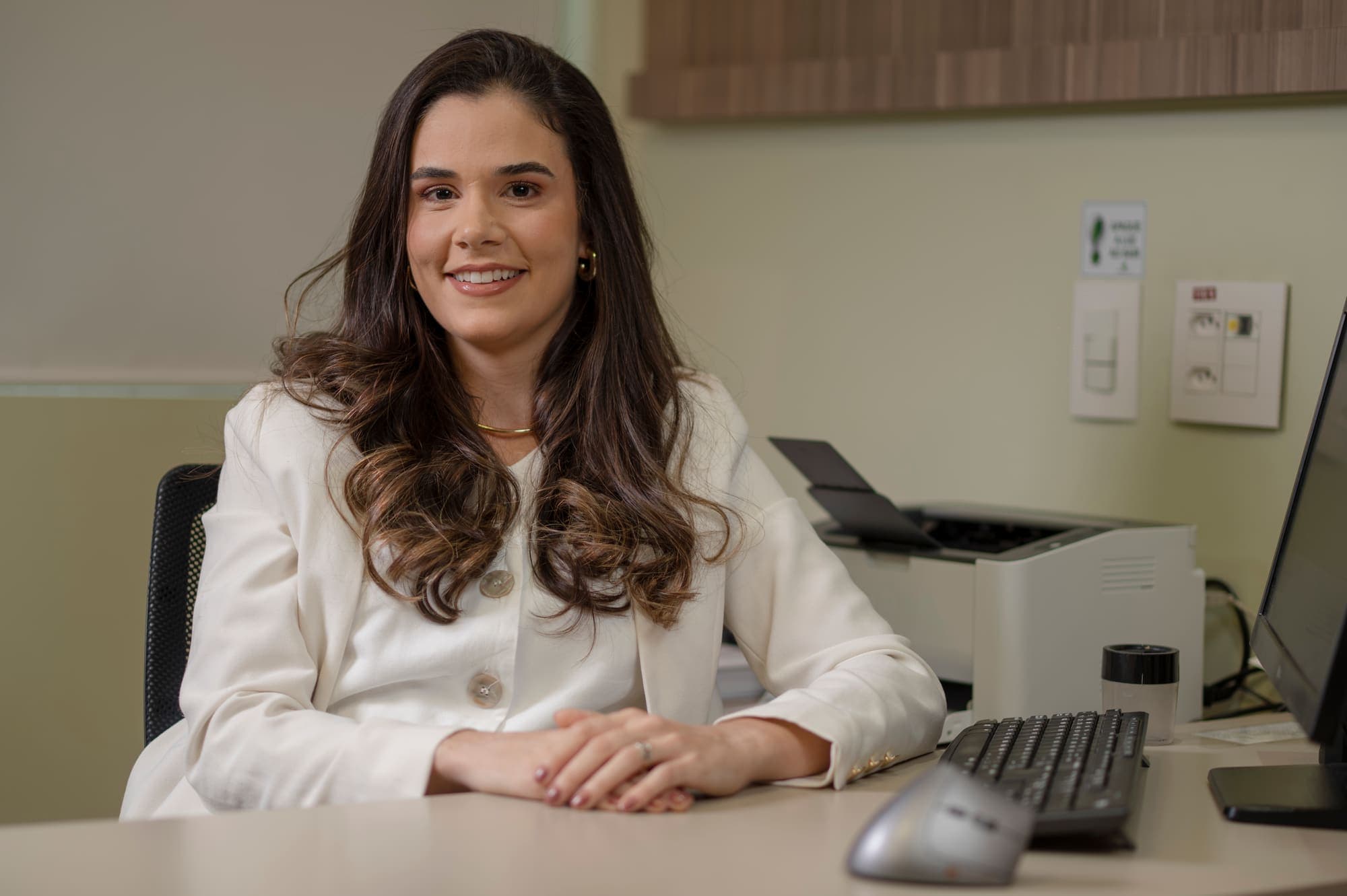 Dra. Mariana Lopes sorrindo em sua mesa no consultório