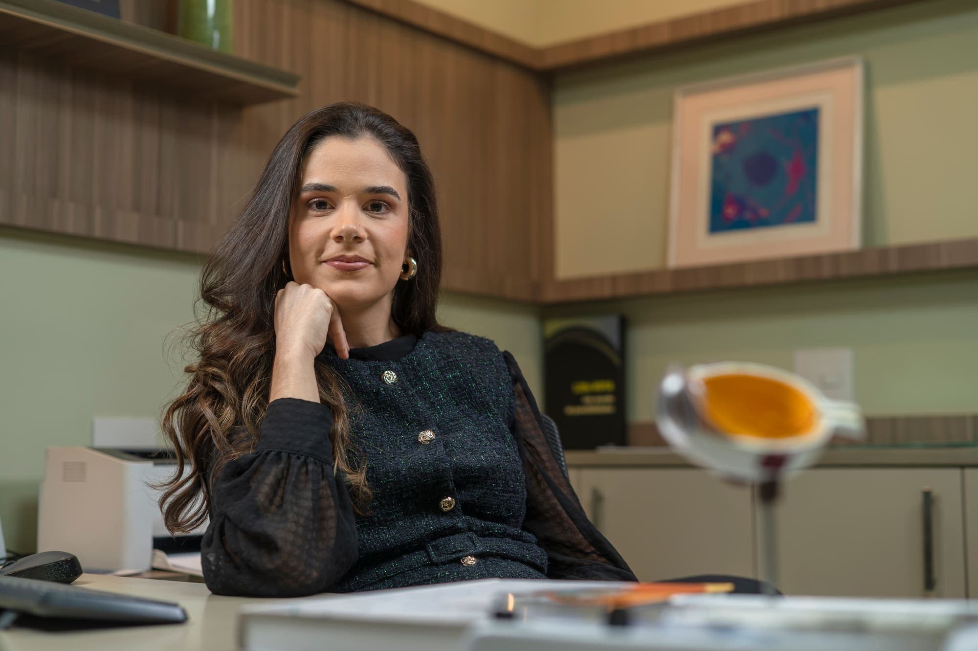 Dra. Mariana Lopes sentada à mesa, com um modelo de olho em primeiro plano