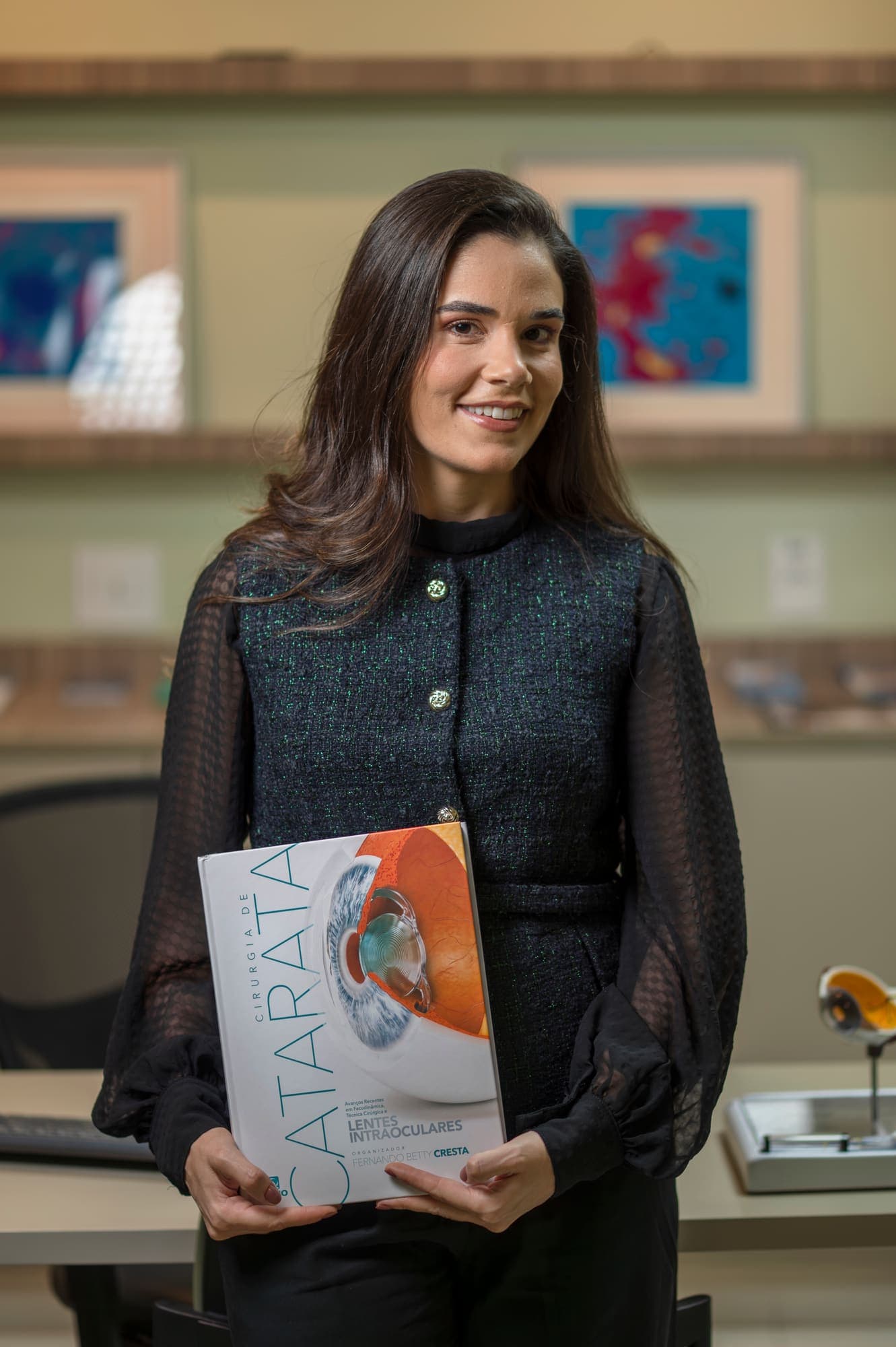Dra. Mariana Lopes segurando o livro de cirurgia de catarata do qual é coautora
