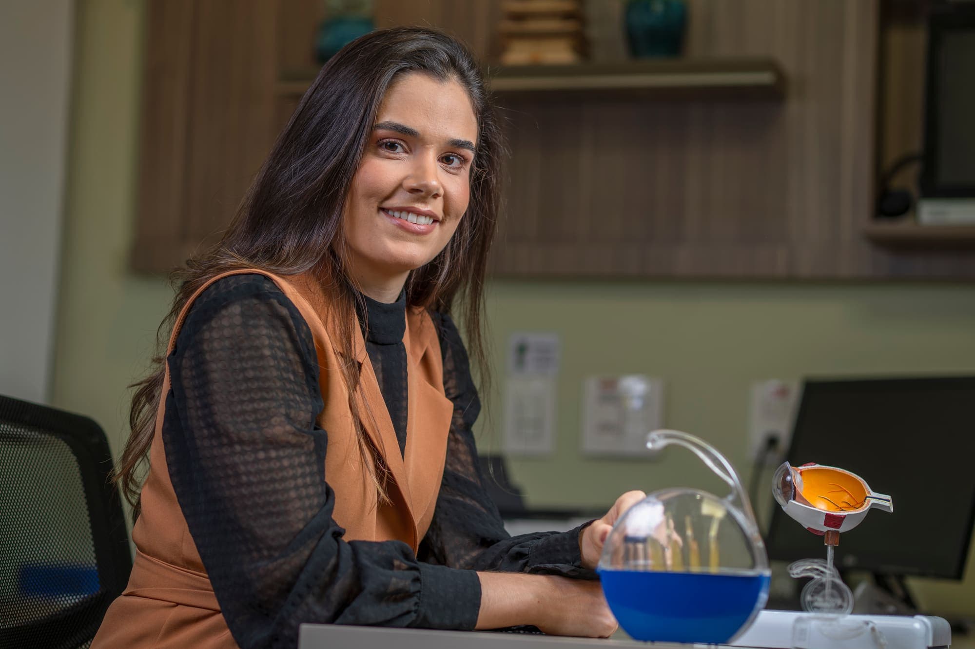 Dra. Mariana Lopes com um modelo anatômico do olho sobre a mesa